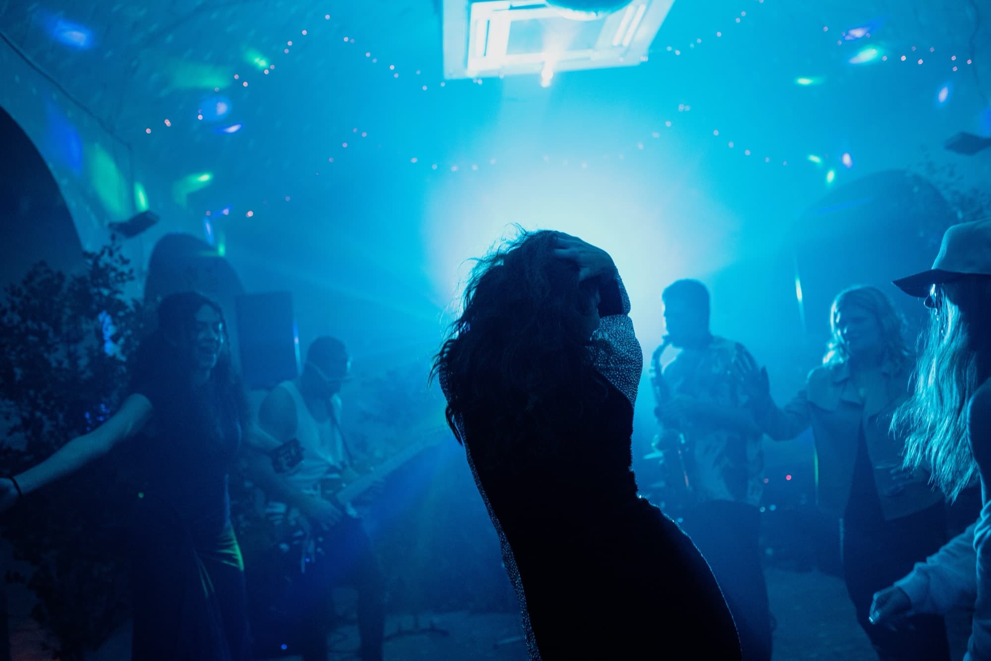 Wedding sax player walking into the crowd at a destination wedding in Spain during a DJ live set